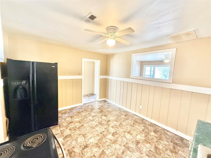 Kitchen featuring black fridge, wainscoting, and visible vents
