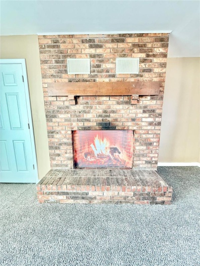 Room details featuring carpet floors, a brick fireplace, and baseboards