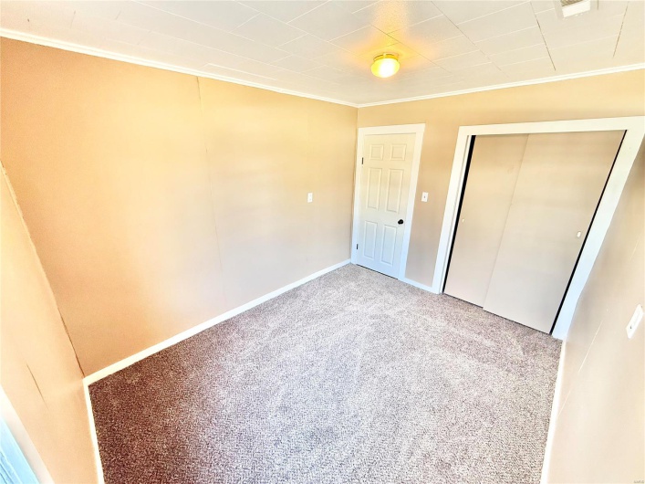 Unfurnished bedroom with baseboards, a closet, carpet flooring, and crown molding