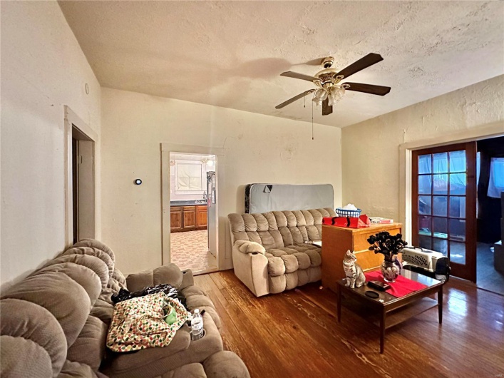 Living room featuring ceiling fan, hardwood / wood-style flooring, and a textured ceiling