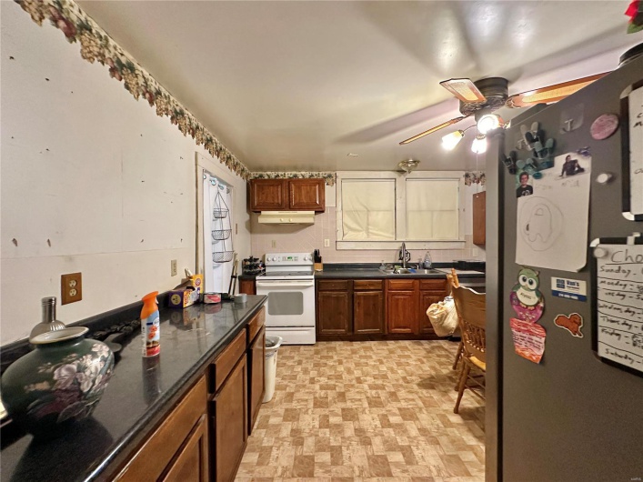 Kitchen featuring stainless steel refrigerator, white electric stove, and sink