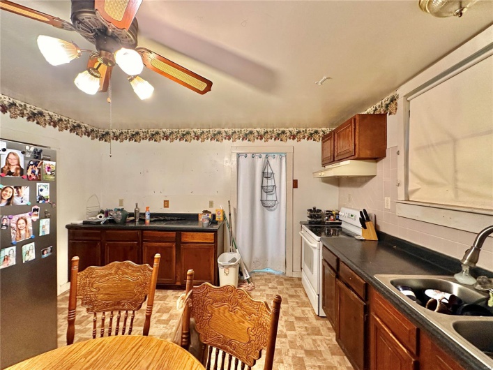 Kitchen featuring stainless steel refrigerator, backsplash, white electric range, ceiling fan, and sink