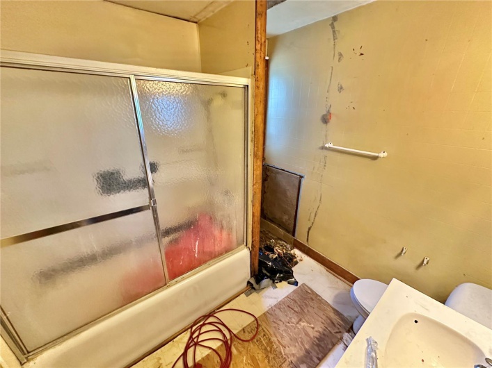 Bathroom featuring combined bath / shower with glass door and toilet