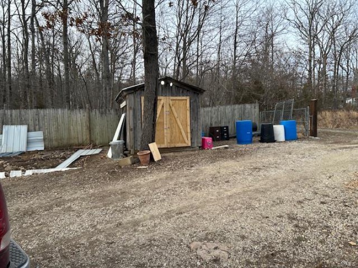 View of yard with a storage unit, fence, and an outdoor structure