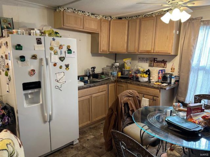 Kitchen with ceiling fan, white fridge with ice dispenser, and dark countertops