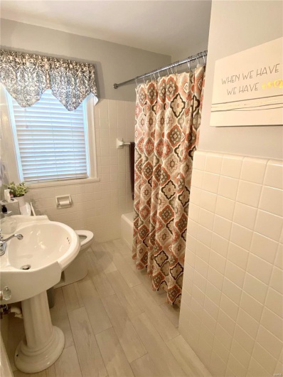 Full bathroom with toilet, shower / bathtub combination with curtain, and tile walls