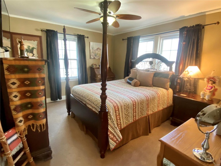 Carpeted bedroom featuring ornamental molding, multiple windows, and ceiling fan
