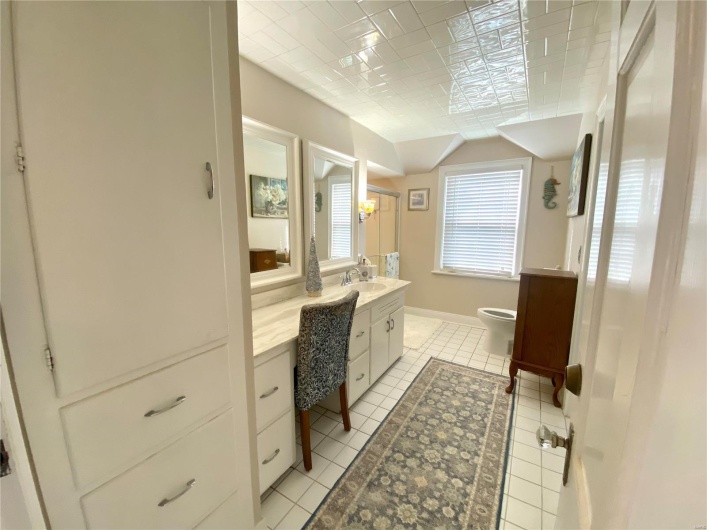 primary bathroom with shower, toilet, tile patterned floors and ceiling, and vanity with makeup counter