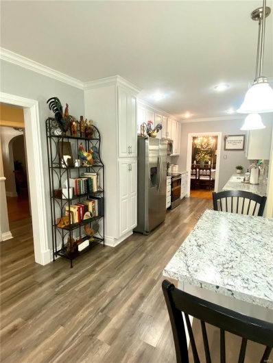 Kitchen with arched walkways, crown molding, stainless steel appliances, light countertops, and white cabinets