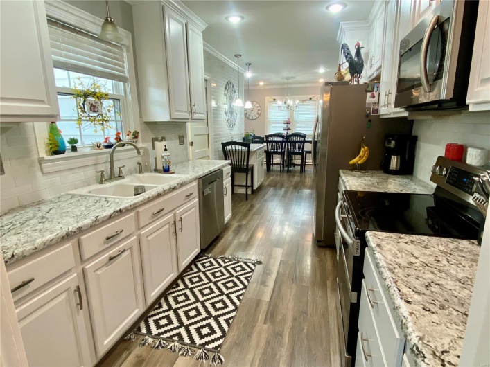 Kitchen featuring wood finished floors, appliances with stainless steel finishes, a sink, and white cabinets