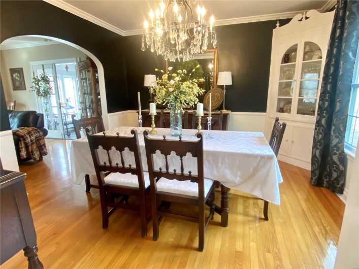 Dining room featuring a wainscoted wall, arched walkways, wood finished floors, and ornamental molding