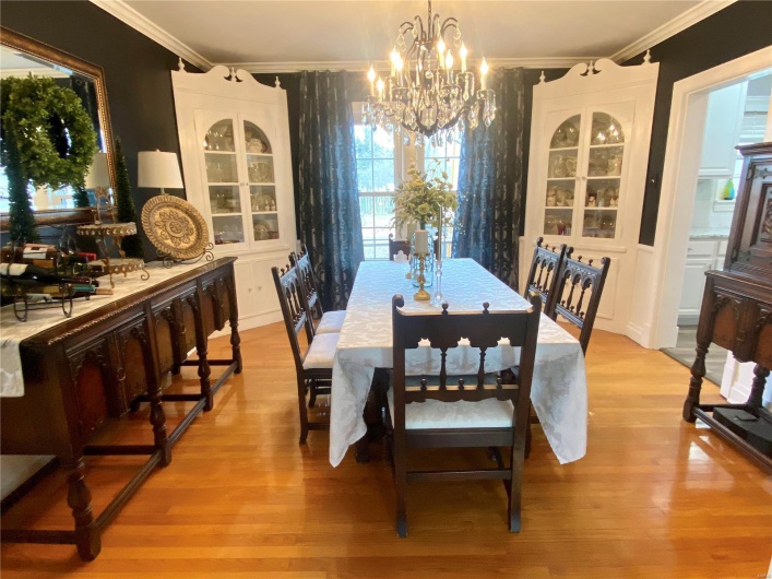 Dining area with built in china cabinets, crown molding, and a chandelier