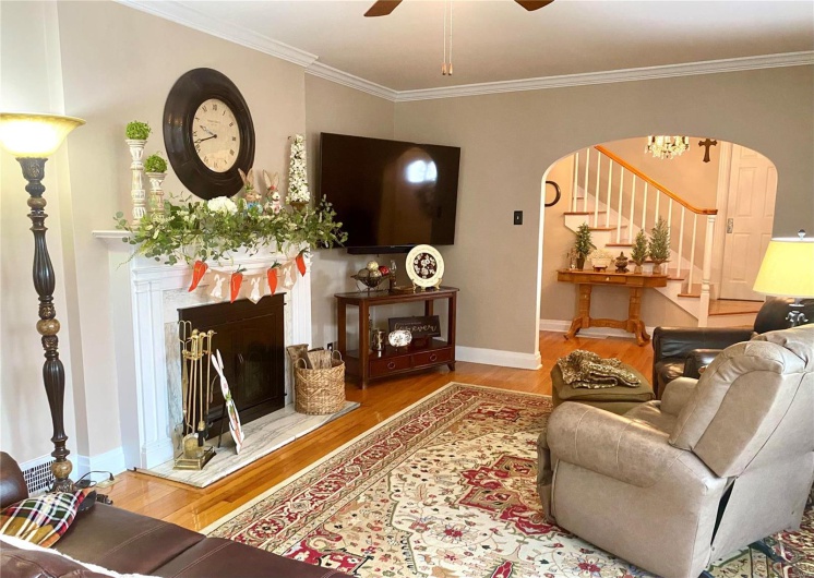 Living area featuring arched walkways, stairway, a premium fireplace, and wood finished floors