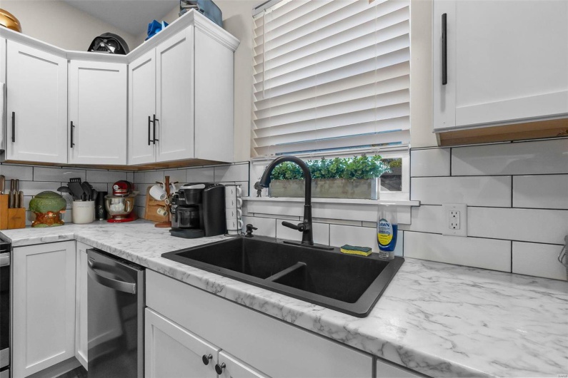 Kitchen featuring backsplash, white cabinetry, dishwasher, and sink