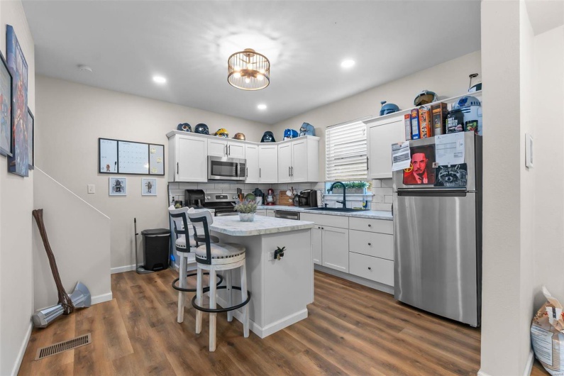 Kitchen with appliances with stainless steel finishes, white cabinets, a kitchen island, a breakfast bar area, and sink