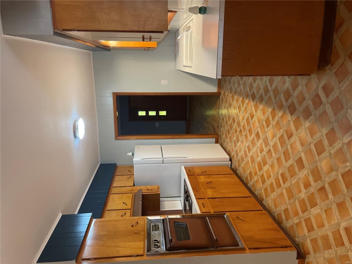 Kitchen with light countertops, a warming drawer, a sink, freestanding refrigerator, and wall oven