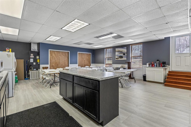 Kitchen with a drop ceiling, dark cabinets, light wood-style floors, freestanding refrigerator, and a center island