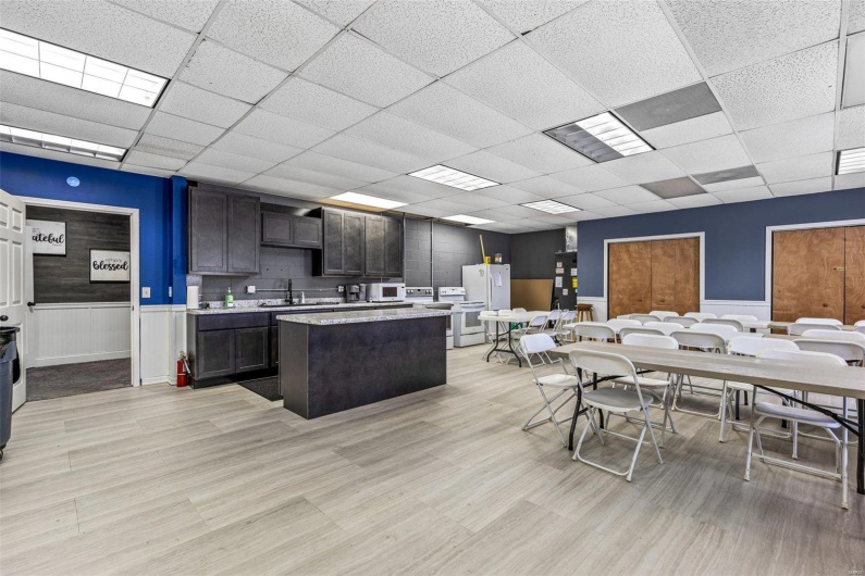 Kitchen with a center island, a wainscoted wall, a paneled ceiling, light countertops, and a sink