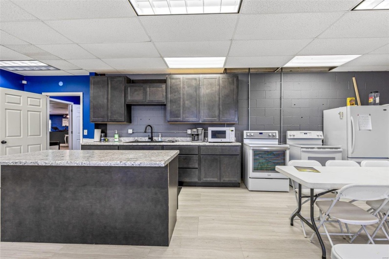 Kitchen featuring dark brown cabinetry, white appliances, a sink, visible vents, and concrete block wall