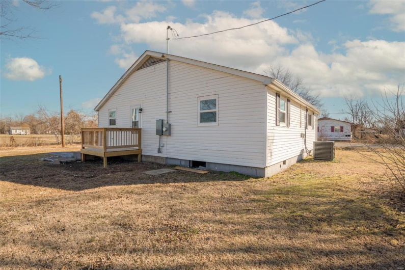 Back of house featuring a deck, a yard, and central AC unit