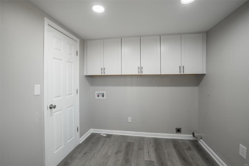 Laundry room with hookup for an electric dryer, washer hookup, wood finished floors, baseboards, and cabinet space