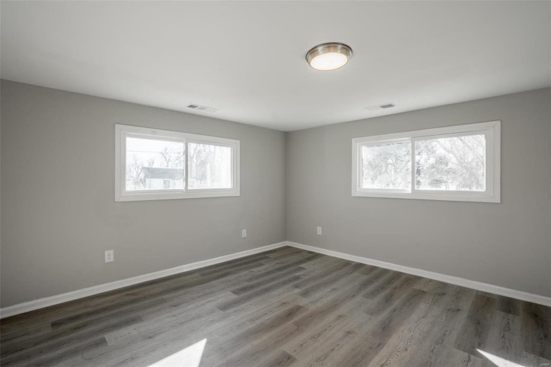 Unfurnished room featuring visible vents, baseboards, and wood finished floors