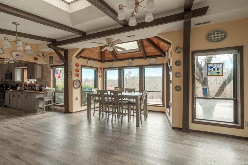 Dining room with visible vents, baseboards, ceiling fan, lofted ceiling with skylight, and light wood-style flooring