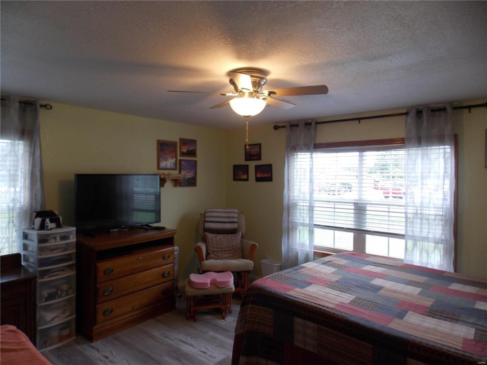 Bedroom featuring light wood finished floors, a textured ceiling, and ceiling fan