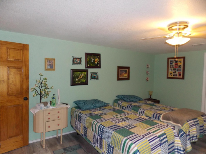 Bedroom featuring ceiling fan, a textured ceiling, and wood finished floors
