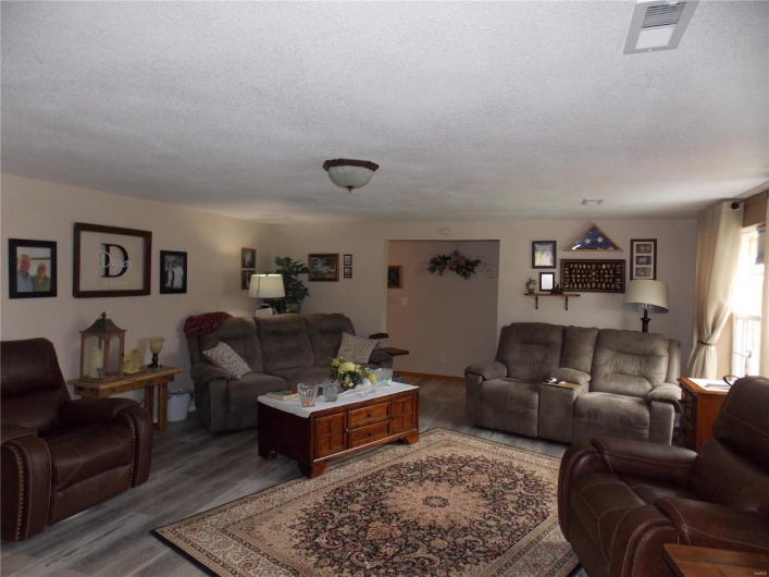 Living area with wood finished floors, visible vents, and a textured ceiling