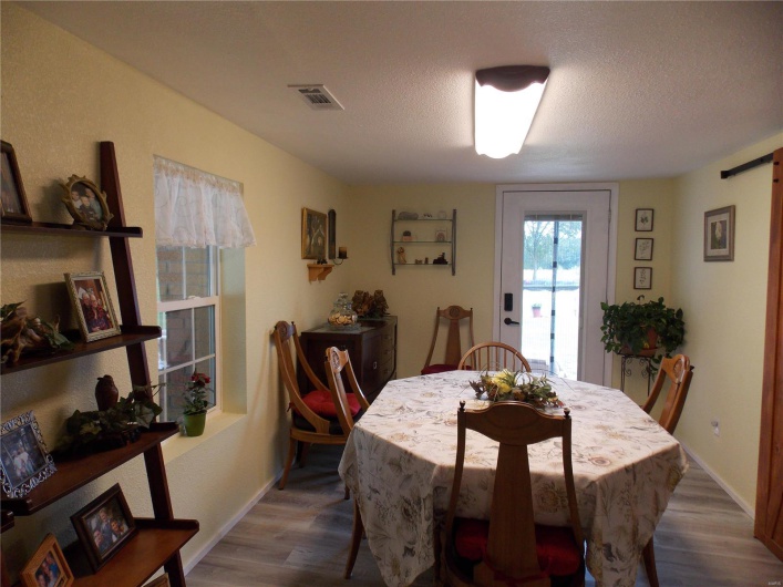Dining space featuring visible vents, a textured ceiling, baseboards, and wood finished floors