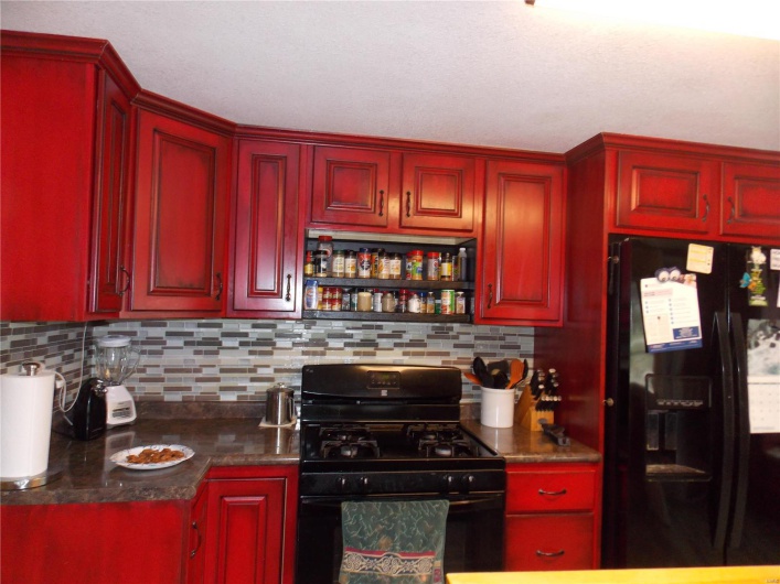 Kitchen featuring dark brown cabinets, decorative backsplash, dark countertops, and black appliances
