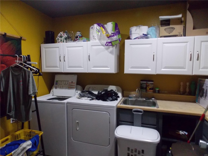 Washroom featuring separate washer and dryer, cabinet space, and a sink