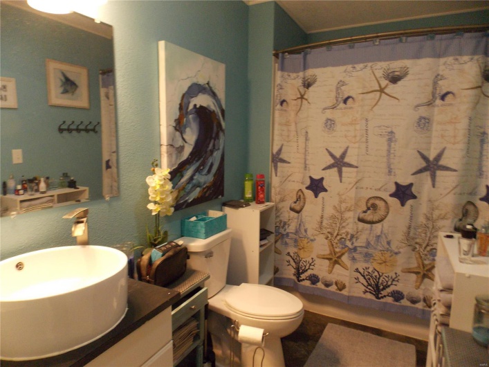 Full bath with vanity, curtained shower, toilet, and a textured wall