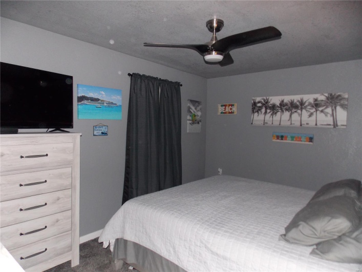 Carpeted bedroom featuring baseboards, a textured ceiling, and ceiling fan
