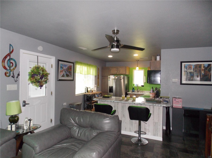 Kitchen featuring a breakfast bar, light countertops, open floor plan, and stainless steel fridge