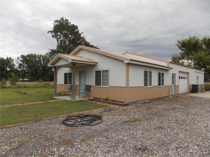 View of front of house featuring an attached garage, metal roof, driveway, and a front lawn