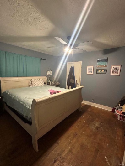 Bedroom with baseboards, a textured ceiling, dark wood finished floors, and a ceiling fan