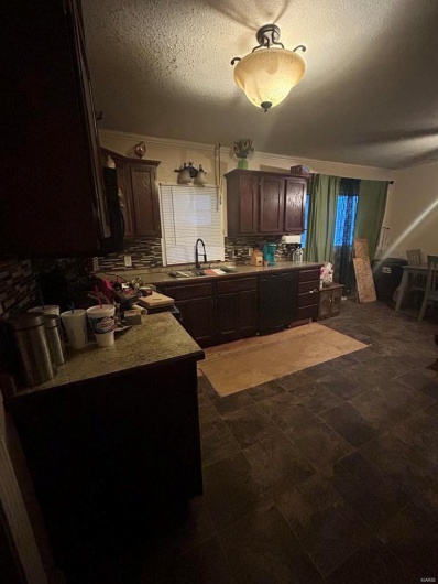 Kitchen with tasteful backsplash, dark brown cabinetry, light countertops, a textured ceiling, and a sink