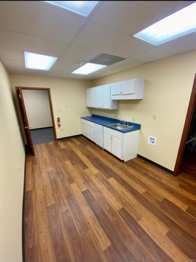 Kitchen featuring dark countertops, dark wood-type flooring, dishwasher, white cabinetry, and a sink