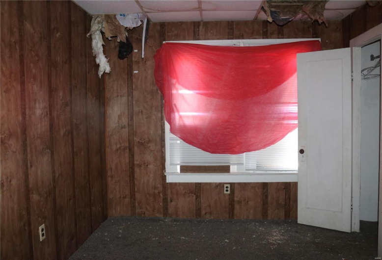 Downstairs Bedroom #1 details featuring a paneled ceiling and wood walls