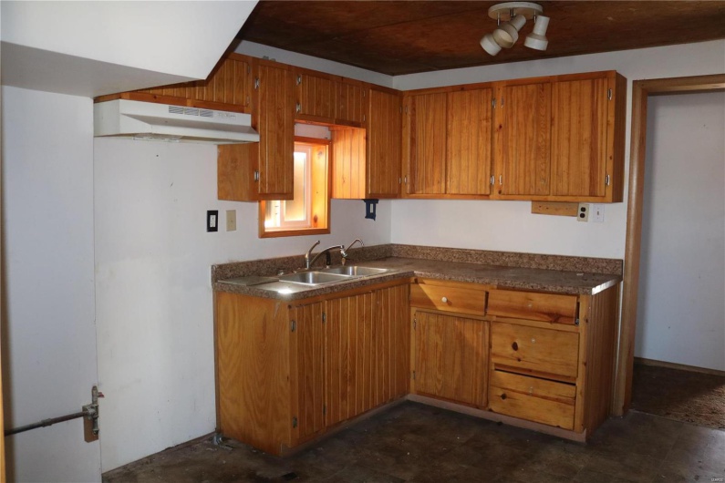 Downstairs Kitchen featuring a sink, brown cabinets, dark countertops, and under cabinet range hood