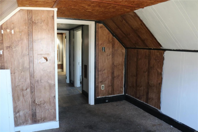 Upstairs Bedroom #1 featuring lofted ceiling and wooden walls