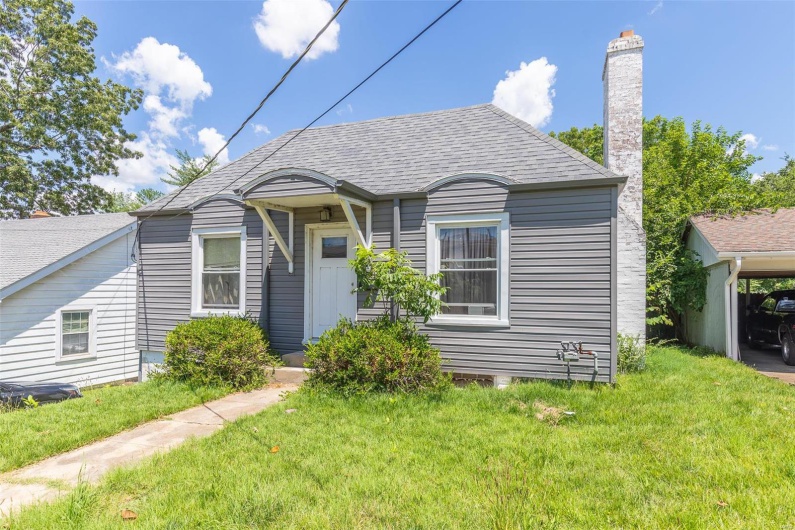 Bungalow-style home with a chimney, a shingled roof, and a front lawn