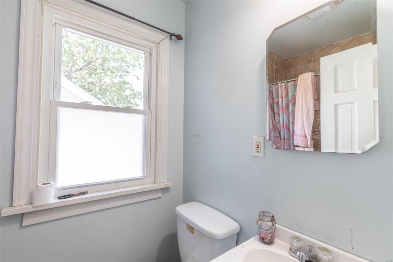 Bathroom with curtained shower, toilet, and a sink