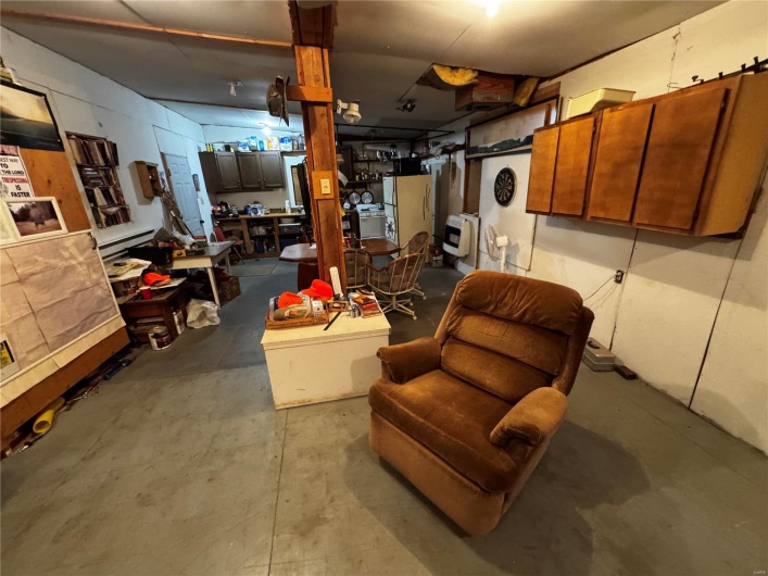 Below grade area featuring heating unit and freestanding refrigerator