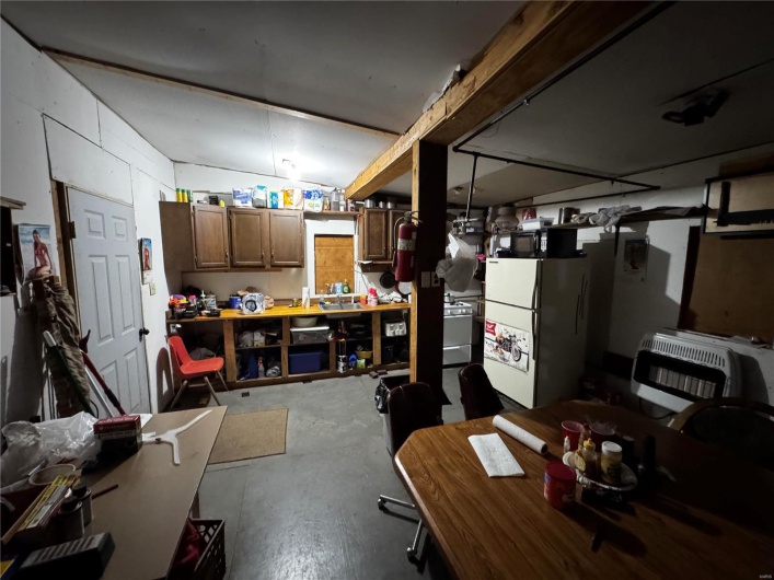 Basement featuring heating unit, a workshop area, and freestanding refrigerator