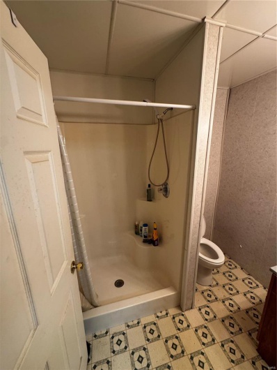 Full bathroom with tile patterned floors, a shower stall, and toilet