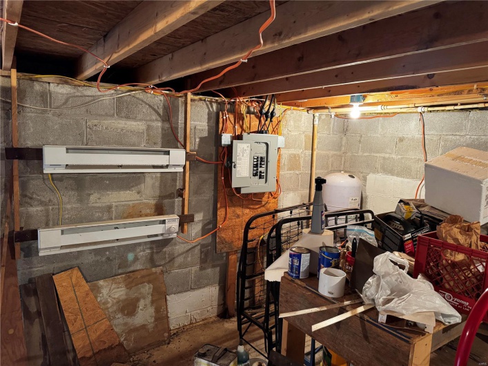 Unfinished basement with electric panel and a wall mounted AC