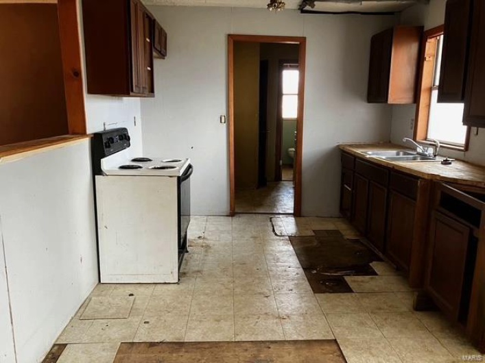Kitchen featuring dark brown cabinetry, electric range, and a sink